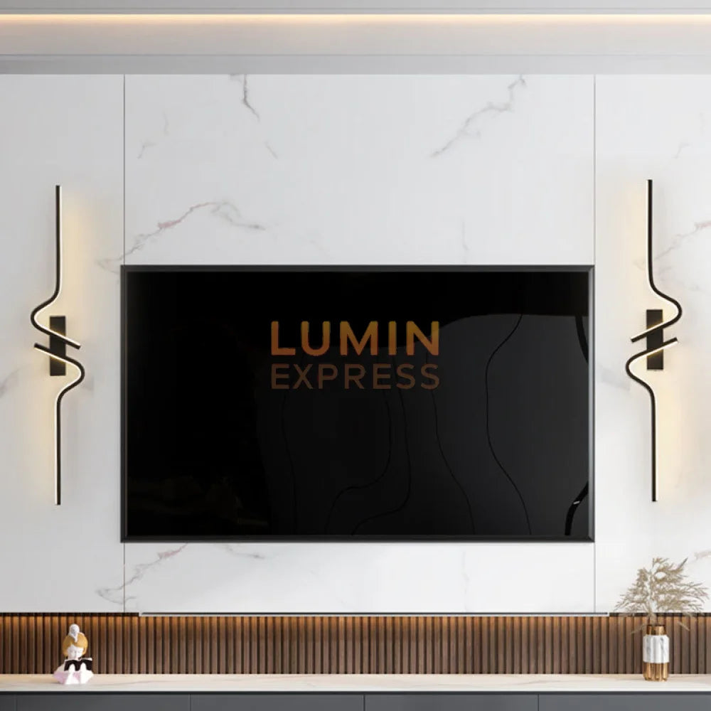 Luminaire mural noir à forme ondulée SERPENTA illuminant un escalier intérieur.